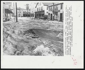 Too Much Water-- Water from a broken dam rushes down the business section of this city here yesterday. Sidewalks and pavements were swept away by the force of the water.