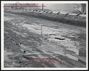 Rough Going was created for motorists yesterday by the rain and ice storm and broken pavements. The water-filled holes are on Commonwealth avenue, Allston, near the Cottage Farm bridge.