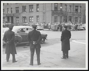 Keeping the Peace -- Special duty policemen stand guard before the garage of the Checker & Taxi Company as a group of AFL Teamsters congregate on the corner of Gainsboro and St. Botolph streets. A crowd of United Mine Workers, which is seeking to take Checker drivers away from the Teamsters, picketed the opposite corner.