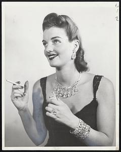 High Class Carbon-Diamonds, which are just hunks of carbon putting on the ritz, according to science, here make a dazzling impression on the eye and the pocketbook. The collection of gems worn by Betty Thompson at the Cartier, Inc., exhibit in New York, is valued at $2,000,000. The ring contains the Mazarin diamond; the ear rings were Marie Antoinette's. The cigarette lighter is frosted with diamonds, too