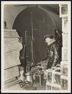 State Trooper John J. Lavezzo of Foxboro barracks inspecting one of the tanks seized in Sharon. This tank was filled with the final run of alcohol, and from it, the cans, seen on the right, were loaded for shipment.