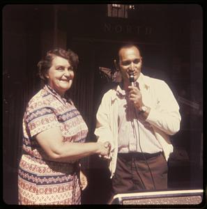 A woman shaking the hand of a man holding a microphone