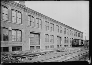 Two story warehouse along railroad spur, showing railroad car 1900-1907