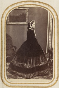 Profile portrait of a standing woman in dress and hat