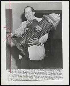 Case of the Portable Fire Hydrant--Joseph Baroncini manages a smile at a police station here today as he dropped by to look over a realistic--but dummy--fire hydrant which was the cause of his auto being tagged for a parking violation Wednesday night. A patrolman ticketed the auto,but on return found the plug and the car had disappeared. On return the next night, the patrolman found the plug against and on inspection found it to be a phony--apparently a TV or stage prop. Baroncini said his car was parked by a doorman, and meanwhile he is due in Traffic Court Mar. 17 to answer a summons