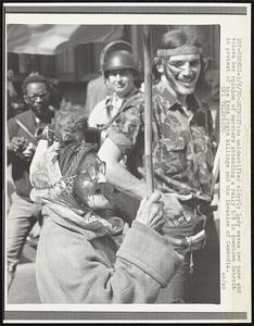 An unidentified elderly lady waves her cane and voices her opinion of marchers attending a rally 5/8 in downtown Detroit in protest of the Kent State killings and the invasion of Cambodia.