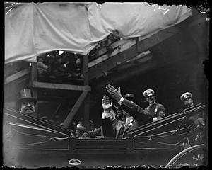 Unidentified man clapping from a car with its roof down