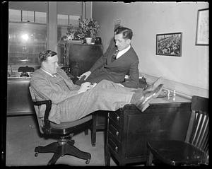 Two men speaking together seated at a desk