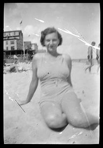 A woman in a bathing suit poses on a beach