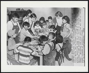 Fun at Refugee Center--Kathleen Damme (center, left), 16, and Lavonne Smith (white blouse right), 14, high school girls, supervise play as a group of little Indian children crowd around play table at refugee center today. Children are from families who had to leave homes because of current flood.