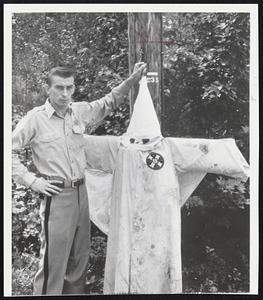 Maine Scene--Sheriff's Deputy Carl Churchill displays Ku Klux Klan cape and hood he cut down from 20 feet up the utility pole near a beach at Hollis, Me., where a Negro was told on Friday to keep his family away from white people. The Klan in the 30's claimed it had 25,000 members in Maine.