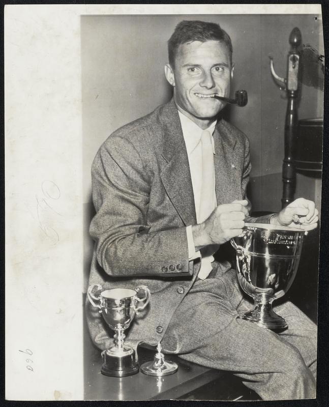 American Trophy Collectors return loaded with British spoils. Ted Schroeder (left) displays his tennis trophies for winning the Wimbledon championship while Jack Kelly is equally burdened with awards he won in the Diamond Challenge Sculls at Henley, his second win in three years.