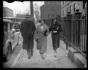 Two women and a man walking down a street