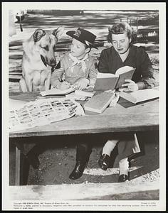 Rin Tin Tin and "Corporal Rusty" (Lee Aaker) take time out during the filming of the "Legacy of Sean O'Hara" the July 22 episode in Screen Gems' Adventures of Rin Tin Tin series, to get a little book learning from Miss Majorie Tate, Lee's tutor on the Screen Gems' set.