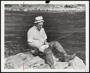 Columnist Bob Elliot studies fly-book to entice landlocked salmon and trout at East Outlet Moosehead Lake, where season begins May first.
