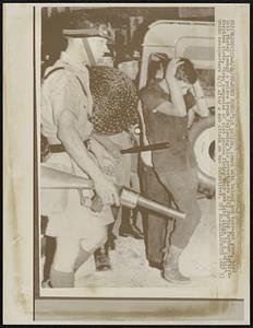 Riot police, armed with batons and tear-gas guns, herd this rioter toward a police truck following his arrest here 6/23 during further leftist-inspired riots. Three companies of riot police firing tear gas laid siege to a leftist union headquarters 6/23 after a mob attack on two detectives.