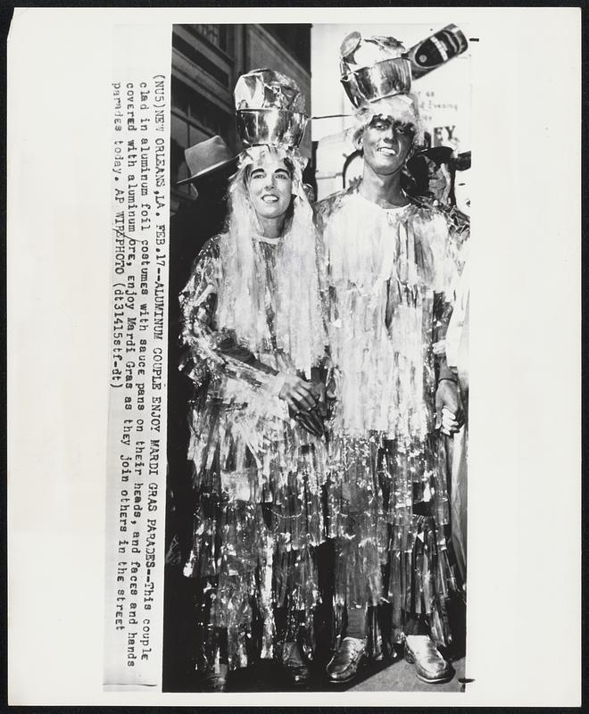 Aluminum Couple Enjoy Mardi Gras Parades--This couple clad in aluminum foil costumes with sauce pans on their heads, and faces and hands covered with aluminum ore, enjoy Mardi Gras as they join others in the street parades today.