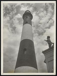 A Famous Beacon, from a Worm's Point of View. Norman B. Devine Jr, son of the keeper of the big lighthouse at Fire Island, N.Y. points upward to the powerful light which warns incoming liners of their approach to the port of New York.