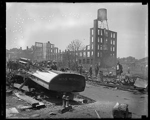 People looking at rubble and debris, possibly after a fire or explosion