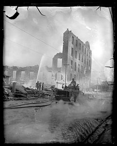 Firefighters using water hoses on the remains of a building