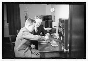 A boy sitting next to a man using an unidentified device