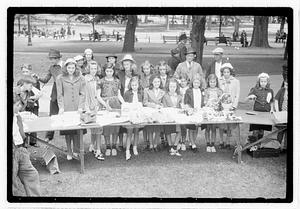 A group of girls behind a collection of items including flowers and baskets