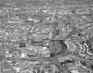 Looking north from Pawtucket Canal past gas tanks to big view of Lowell