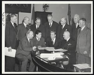 At Fuel Crisis Conference in the mayor's office today were (standing, left to right): Leo Power, superintendent of buildings; Police Commissioner Sullivan, Arthur L. Gould, superintendent of schools; William G. O'Hare, welfare department secretary; William P. Morrissey, public works commissioner; William L. Kendricks, fuel engineer, and Alexander M. Sullivan, school department business manager. Seated (left to right): Dr. James W. Manary, City Hospital superintendent; Joseph F. White, fuel advisor to the city; Mayor Kerrigan and Dr. Frederick J. Bailey, health commissioner.