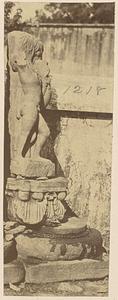 View of damaged sculpture of person and bird-like creature, on pedestal outdoors