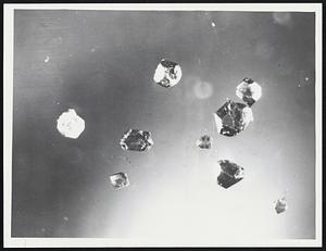 Enlarged photo shows diamonds synthesized from graphite by Army scientists. Largest is about 1/16 of an inch in diameter.