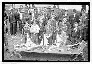 A group of boys behind a collection of model boats