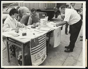 Peace Petition Station in North End of Boston yesterday is manned by Irene Fournier of North Attleboro and Joseph Hurwitz of the Back Bay. Signer is William Scaglione of Arlington.