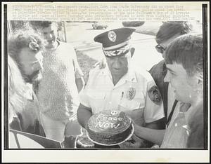 Student protestors from Iowa State University did an about face Friday morning by presenting "Peace Now" chocolate cake to assistant police chief Tom Lyttle at Selective Service office in Ames. The presentation of the cake followed a day of 23 arrests by Lyttle and other officers Thursday when protestors refused to move from blocking selective service entrance. Bearded youth at left was one arrested when tear gas was used.