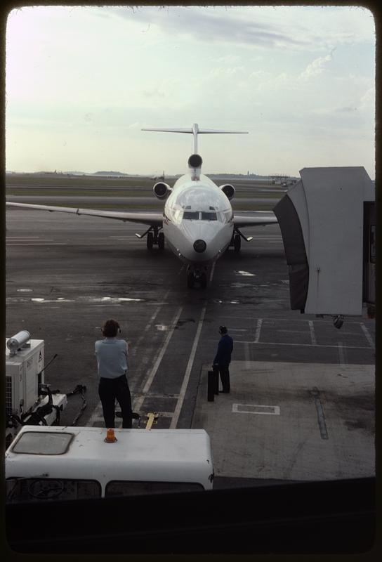 Airplane on airport tarmac heading toward jet bridge