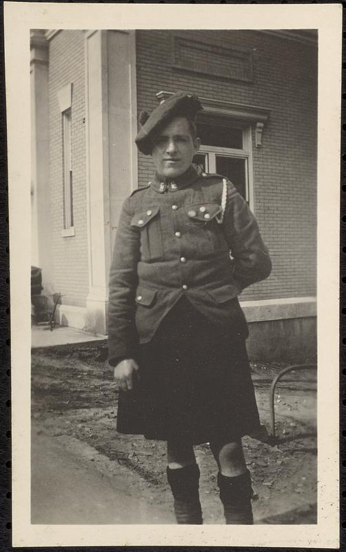 Boy? In uniform (kilts?) beside bank building