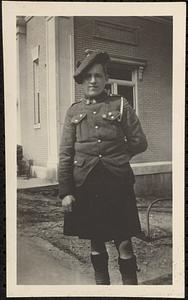 Boy? In uniform (kilts?) beside bank building