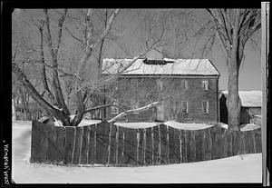 House in snow, scalloped fence in foreground