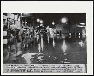 Street Scene -- Flood waters cover center of downtown Norwich today, after park dam burst, sending waters on rampage through city. Water entered most stores in center of city.