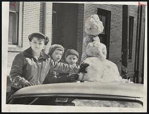 Traveling Snowman - These youngsters on Bunker Hill road, Charlestown, felt that anybody can build a snowman on the ground so they built theirs on the roof of a car. Left to right, James DiVola, Kathleen and Joseph Malone.