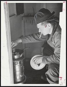 Ice Fishing in a shack on Lake Winnipesaukee - N.H. Dick Barton - Lakeport N.H. gets his meal on portable stove.