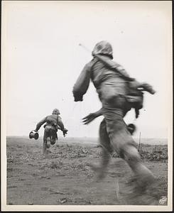 Two marine wiremen on Iwo Jima race across an open field under heavy enemy fire to establish field telephone contact
