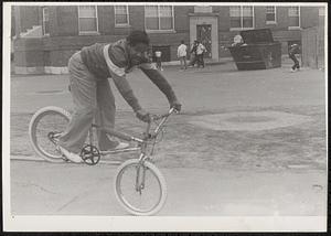 Young man doing bike tricks in courtyard