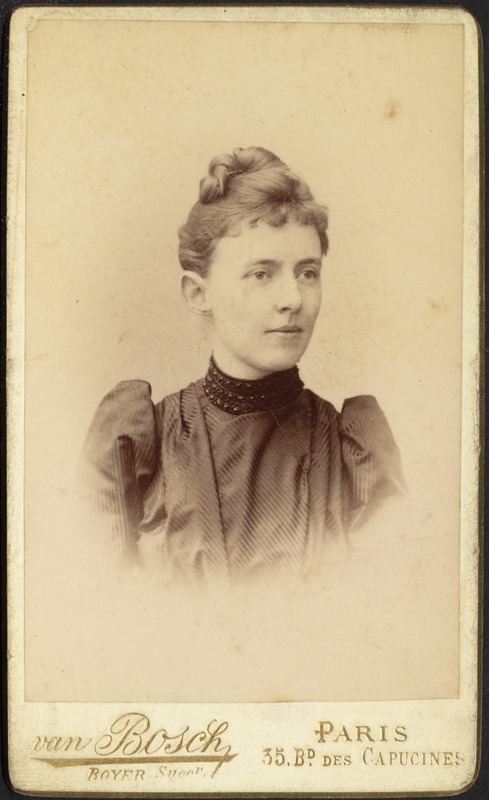 Young woman in dark dress with strips; hair in top knot