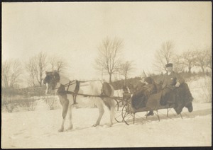 Man in fur hat and two small children in pony-drawn sled