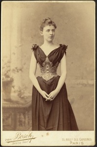 Young woman in dark dress with elaborate corselette
