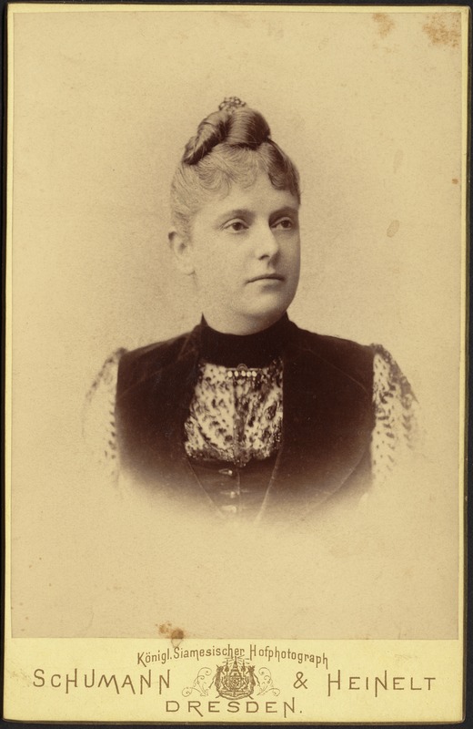 Young woman in high collar dress with black velvet vest