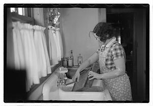 A woman doing laundry at a sink with a washboard