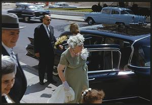 People in formal dress getting out of a car at sidewalk