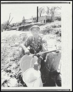 Sixty-nine-year-old Peter J. Vatern smiles as he gets his first clean water in several days here 8/19 from a newly found well. The City of Pass Christian once was behind him on the same level as stores still standing. Hurricane Camille demolished this town and claimed several lives in the downtown section.