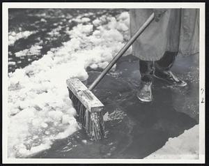 Oh, Slush!!-That was the pedestrian's plaint today as a rain turned a late March snowstorm into a sea of slush which clogged catchbasins and left deep puddles at intersections. Here some of the slush is started on its way down the drain by a street department worker.